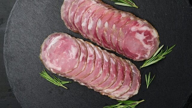 Italian coppa capocollo arrangement on slate with fresh herb garnish