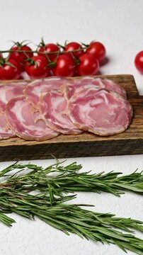 Traditional italian coppa capocollo arrangement with tomatoes and herbs on rustic wooden board