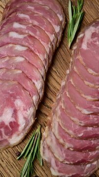Sliced capocollo arrangement with herbs on rustic wooden board