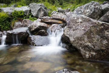 Clear water flowing in a mountain stream, photo taken with a long exposure effect.
