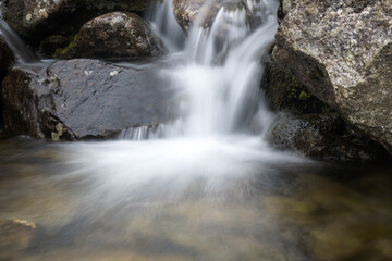 Clear water flowing in a mountain stream, photo taken with a long exposure effect.
