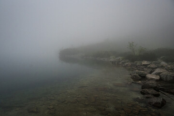 Rocky shore of a mountain lake in the fog, mountain landscape.
