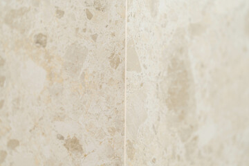 Close-up of beige natural stone wall with subtle texture and joint line — high-end bathroom tile, travertine or marble look, interior design surface, real estate and decor detail