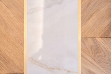 Elegant floor detail with marble inlay and brass framing on chevron wood — luxury interior...
