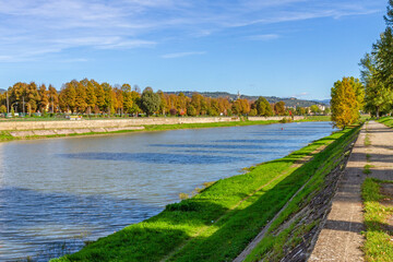 Autumn river landscape with trees, clear sky and walking path.