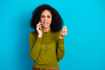 Young woman expressing emotion while talking on a phone against a vibrant blue background