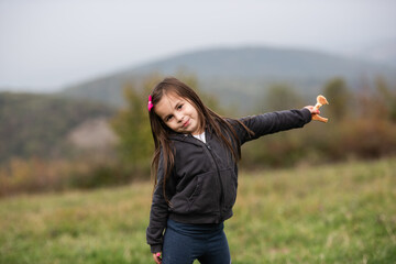 Little girl holding mushroom in a meadow on cloudy day
