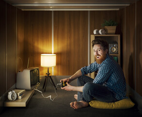 Cheerful man playing video games in a tiny living room