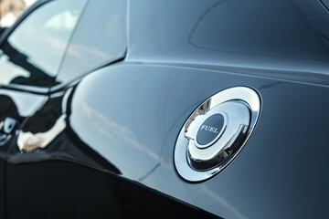 Glossy fuel cap with engraved “FUEL” text on a black surface, showcasing metallic reflections...