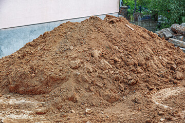 A large pile of earthy soil and small rocks sits in an outdoor construction site, ready for...