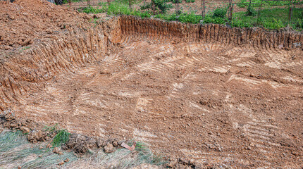 A wide trench filled with loose soil and surrounded by grass and a fence highlights an active...