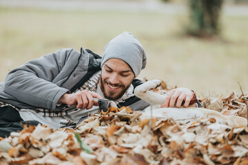 A man enjoys autumn by playing and bonding with his dog in fallen leaves outside. The image conveys...