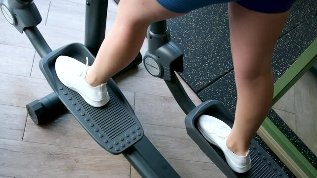 Young woman working out on orbi track at gym exercising
