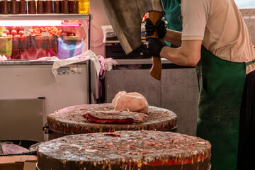 Butcher cutting fresh meat with cleaver at traditional butcher shop counter