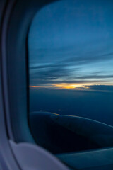 Fototapeta premium Sunset view of airplane engine and clouds from a window seat during flight