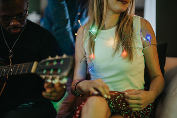 A close-up view of people enjoying a festive, relaxed gathering with guitar music and ambient...