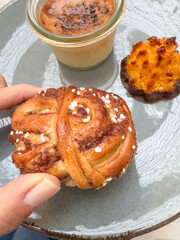 hand holds delicious sweet cinnamon roll from dessert plate