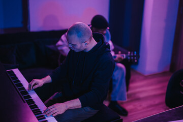 Two musicians passionately creating music in a studio, featuring a pianist and guitarist. The ambient lighting adds a creative atmosphere, emphasizing their focus and musical collaboration in a modern