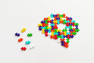 Brain shaped colorful jigsaw puzzle on white background. A missing pieces of the brain puzzle. Mental health and problems with memory.