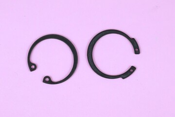 Obraz premium Top view two black Circlip or ring retaining isolated on pink background.