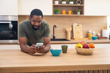 Morning routine, simple living. One man standing in the kitchen, drinking coffee, eating healthy...