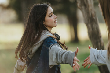Two teenage girls share a joyful moment outside, depicting an atmosphere of friendship and...