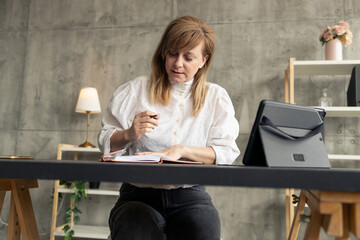 Businesswoman working from home office taking notes and using tablet