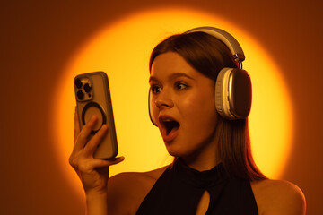 Surprised Woman Using Smartphone and Headphones with Bright Background