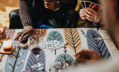 A cozy scene of individuals enjoying a card game, accompanied by glasses of wine and warm...
