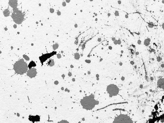 Black and gray ink splatters on a textured white surface create an abstract art composition