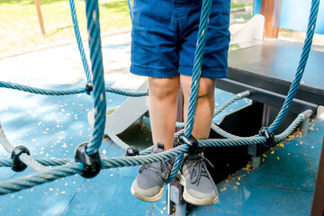 Little toddler kid child boy having fun leisure games passing obstacle course rope adventure park...