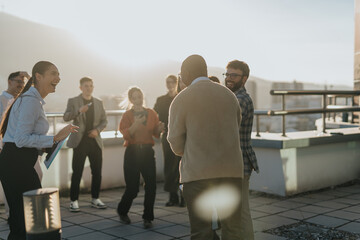 Group of mixed race business colleagues celebrating success on rooftop at sunset