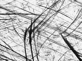 Abstract patterns created by scratches on a textured surface captured in black and white