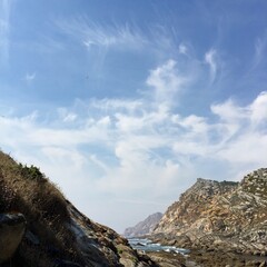 Coastal landscape with rocky cliffs and clear blue sky during midday near the ocean