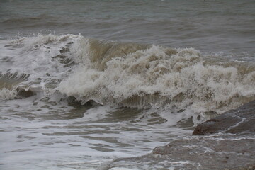 Churning waves crash against rocky shore during a gloomy day at the seaside