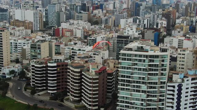 The costa verde-malecon in miraflores, lima, with a paraglider in the city skyline, aerial view