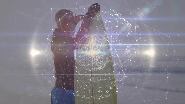 Surfer lifting board on beach and rubbing wax while wireframe globe overlay pulsing in surfing prep
