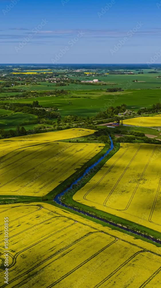 Poster shadows from drifting clouds sweep across wide yellow fields in a scenic hyperlapse.