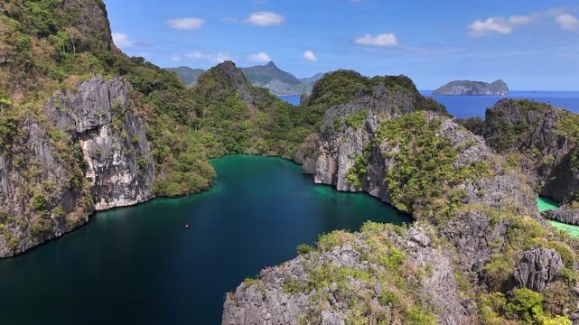 Drone shot over Big Lagoon on Miniloc Island, El Nido, Palawan, showcasing towering karst limestone formations enclosing vibrant turquoise waters linked to the Bacuit Bay of the South China Sea.