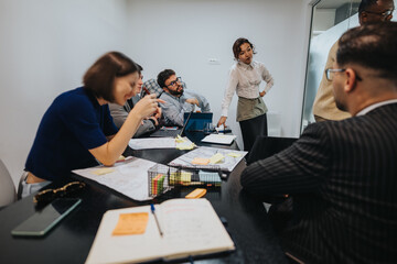 A diverse group of business employees engage in a brainstorming session, analyzing and discussing a...