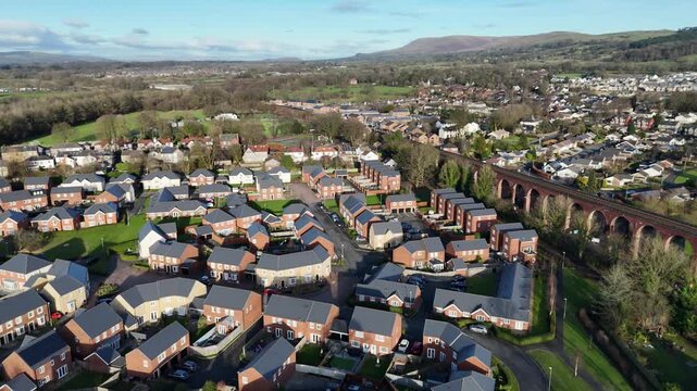 Stunning aerial footage of Conisbrough Viaduct surrounded by quaint homes in South Yorkshire, England. The vibrant landscape, under clear skies, showcases architectural contrasts.