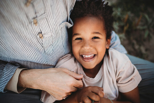 Portrait of black multiracial 5yo boy laughing on dad lap