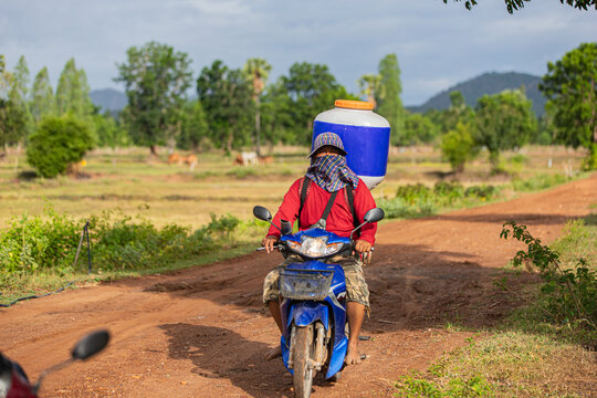 Farmer transporting seed broadcaster by motorcycle