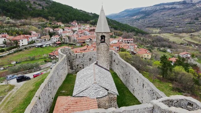 Historic stone church in Črni Kal from air as drone circles spring hillside