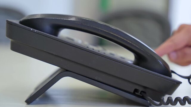 Detailed shot of a hand dialing on a corded office phone, great for business, tech, and communication themes.