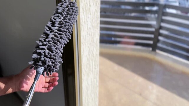 Close-up of chenille microfiber duster at window, ideal for hygiene, home care, and cleaning-themed content.