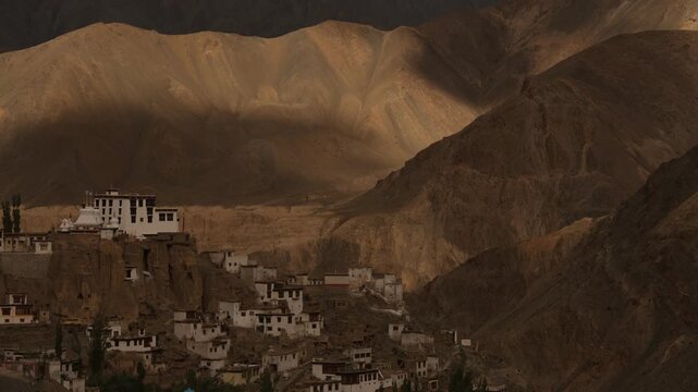 Gompa nestled on cliff with dramatic mountainous landscape, Timelapse with moving shadow and light from dynamic clouds. Close up, copy space.