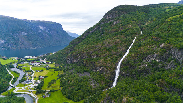 Aerial view of Turlifossen waterfall cascading down lush green cliffs into the fjord, a tapestry of nature's artistry, Aurland, Vestland, Norway.
