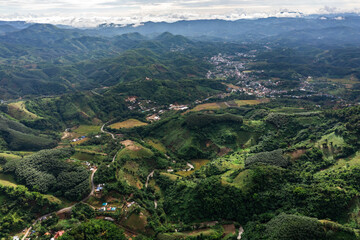 aerial view reveals complex lush green mountain scenery with villages and winding roads amidst abundant nature, reflecting the beauty of rural areas.