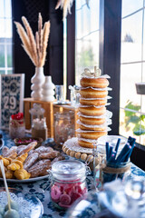 A beautifully arranged table showcases a variety of pastries, including donuts and macarons,...